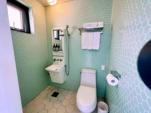a green bathroom with a toilet and a sink at Yaho Beach House in Jeju