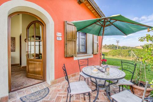 a patio with a table and chairs and an umbrella at Agriturismo Maramaldo - Happy Rentals in Castelfiorentino