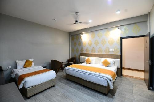 a hotel room with two beds and a television at Hotel Jataka Inn in Bodh Gaya