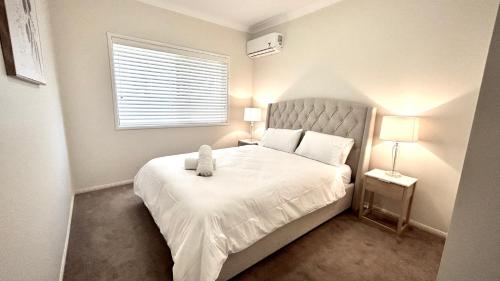 een slaapkamer met een bed met een teddybeer erop bij Perfect North Brisbane Retreat 4 bed in Griffin