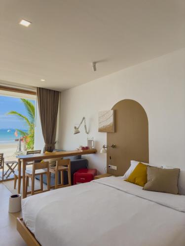a bedroom with a bed and a desk with a view of the beach at lovelytheroom in Ko Lanta