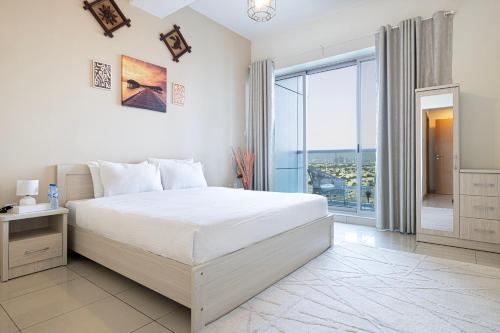 a white bedroom with a bed and a large window at HomesGetaway - Stylish 1BR Armada Cluster P in Dubai