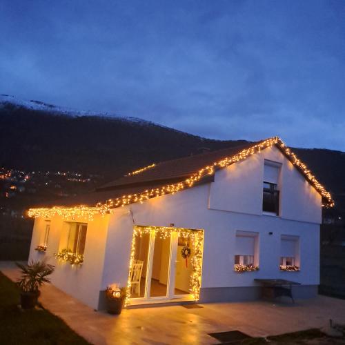 a white house with christmas lights on the roof at Vikendica Bruše in Jaklići