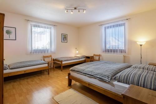 a bedroom with two beds and two chairs and windows at Pension Iveta in Liptovský Mikuláš