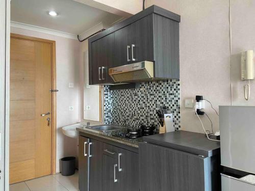 a kitchen with gray cabinets and a sink and a counter at Apt Signature Park Studio H3r1 w/ Wi-Fi & Netflix in Jakarta