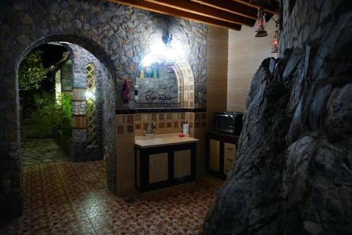a bathroom with a sink and a stone wall at Fort Mughaibar Resort in Hatta