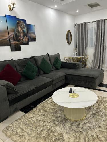 a living room with a black couch and a white table at Deluxe Mansion in Buea