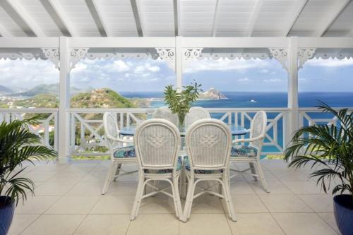 a white porch with a table and chairs and the ocean at Brise De Mer - Villa with captivating views of the Caribbean Sea villa in Cap Estate