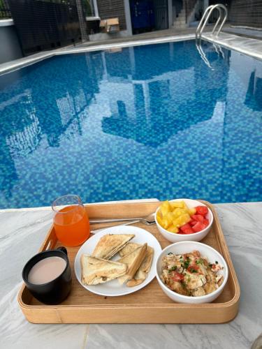 een dienblad met eten op een tafel naast een zwembad bij Deluxe Mansion in Buea