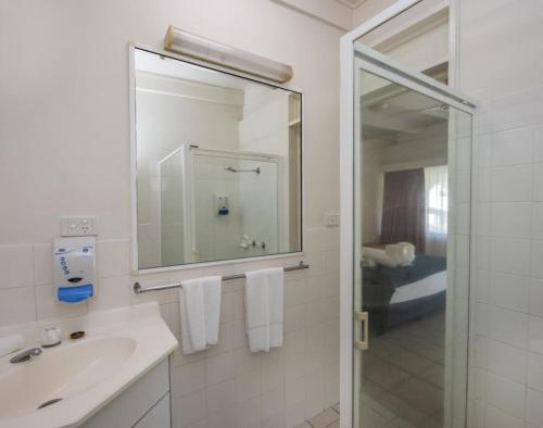 a white bathroom with a sink and a mirror at AFFORDABLE ISLAND ESCAPE! Queen Studio, Nelly Bay in Nelly Bay
