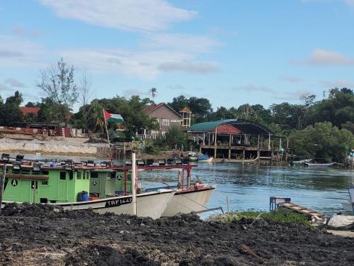 un bateau est amarré sur une rivière avec des maisons dans l'établissement Homestay Cassia Marang, à Marang