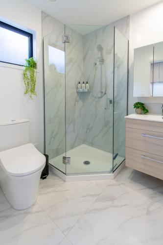 a bathroom with a shower with a toilet and a sink at Botanic Bliss Bungalow: 1 bed loft in Christchurch