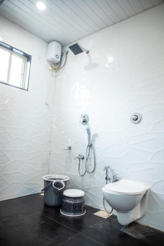 a white bathroom with a toilet and a shower at The Green Jungle Resort in Karjat