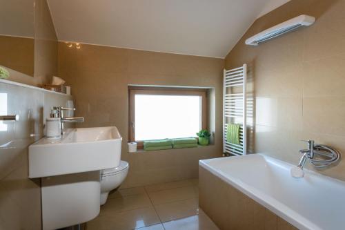 ein Badezimmer mit Badewanne und Toilette und einem Fenster in der Unterkunft Pension Lunatyk in Liptovský Mikuláš