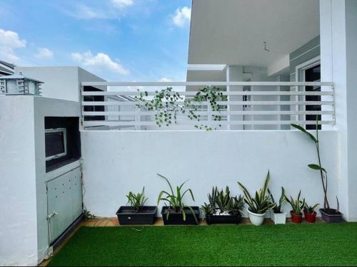 uma varanda com vasos de plantas numa parede branca em Home at Kota Puteri em Batu Arang
