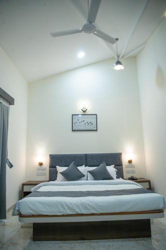 a bedroom with a large bed with a ceiling fan at The Green Jungle Resort in Karjat