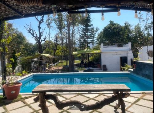 uma piscina com um banco de madeira ao lado em Auspicious villa em Udaipur