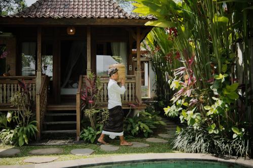 a man standing in front of a house with a box on his head at Anandari Ubud Villa in Ubud