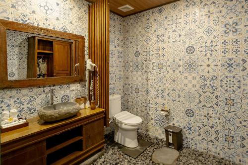 a bathroom with a toilet and a sink and a mirror at Anandari Ubud Villa in Ubud