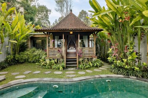 a gazebo in a garden next to a swimming pool at Anandari Ubud Villa in Ubud