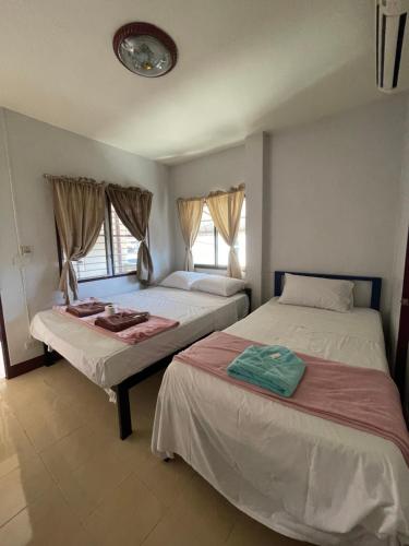 two beds in a room with two windows at JJ Guesthouse in Chiang Mai