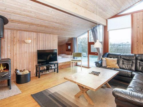 a living room with a leather couch and a fireplace at Secluded Retreat with Sauna - By Traum Ferienwohnungen in Sønderby
