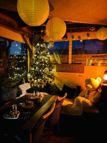 a teddy bear sitting at a table with a christmas tree at Balcsitthon Apartmanok in Siófok
