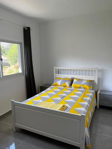 um quarto com uma cama com lençóis amarelos e brancos e uma janela em VILLA NAYELI Luxury and Simplicity em Órgãos