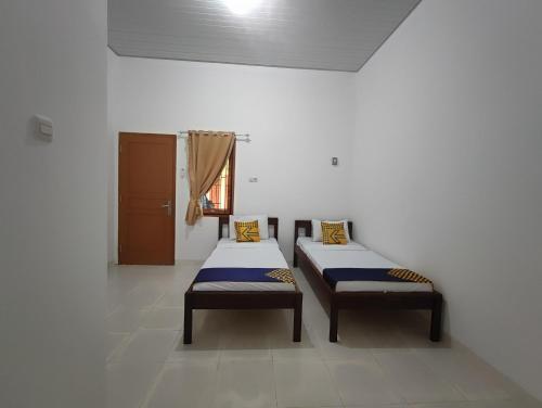 two beds sitting in a room with a window at SPOT ON 93350 Alnasya Syariah in Palembang