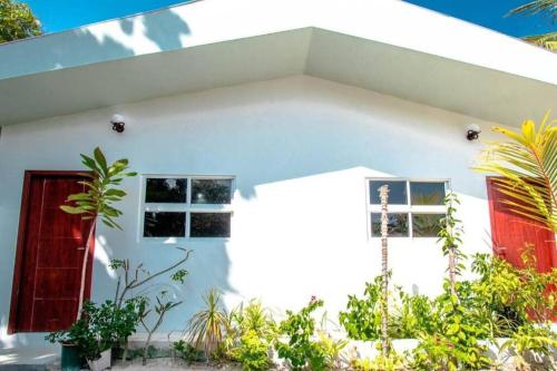 a white house with red doors and plants at Amore Apartment, Maldives in Dhangethi