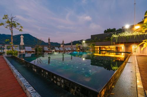 - une piscine de nuit avec des montagnes en arrière-plan dans l'établissement Rak Elegant Hotel Patong - SHA Extra Plus, à Patong Beach