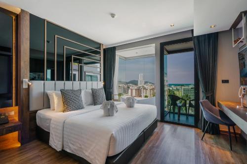 - une chambre avec un grand lit et un balcon dans l'établissement Rak Elegant Hotel Patong - SHA Extra Plus, à Patong Beach