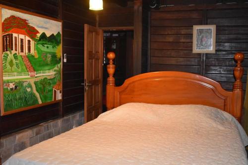 a bed in a bedroom with a painting on the wall at Habitation Bonneville Chalet & Loft avec piscine et sauna in La Trinité