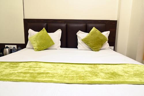 a bed with white sheets and green pillows at Hotel Pulse Inn- Near Jaipur Railway Station in Jaipur