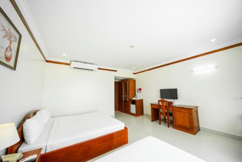 a bedroom with a bed and a desk and a tv at Pursat Riverside Hotel & Spa in Pursat