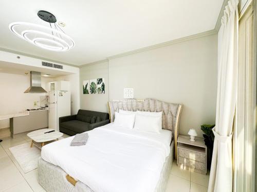 - une chambre avec un grand lit blanc et un canapé dans l'établissement Studio at Spring Oasis Dubai Silicon Oasis By ANW Vacation Homes, à Dubaï