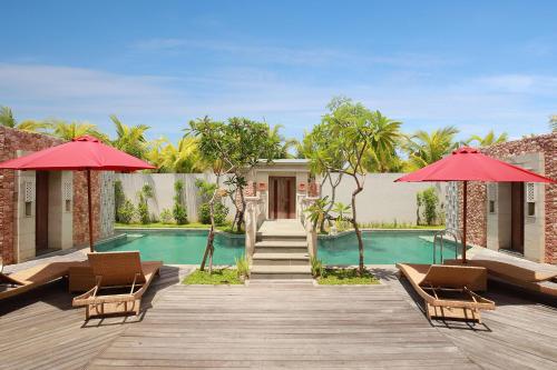 a resort with a pool and red umbrellas at Vivara Bali Private Pool Villas & Spa Retreat in Jimbaran