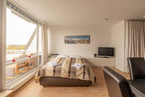 a bedroom with a bed and a large window at Sonnenanbeter in Strande