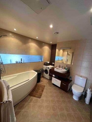 ein Badezimmer mit einer Badewanne, einem WC und einem Waschbecken in der Unterkunft 1-bedroom apartment near airport in Petrikyula