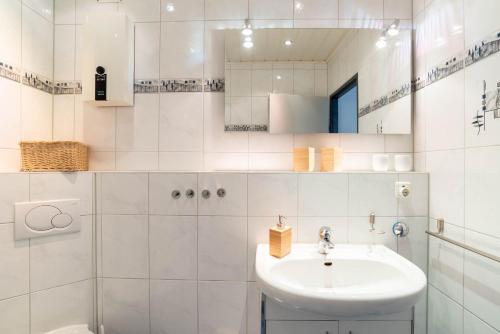 ein weißes Badezimmer mit einem Waschbecken und einem Spiegel in der Unterkunft WestSide in Schilksee