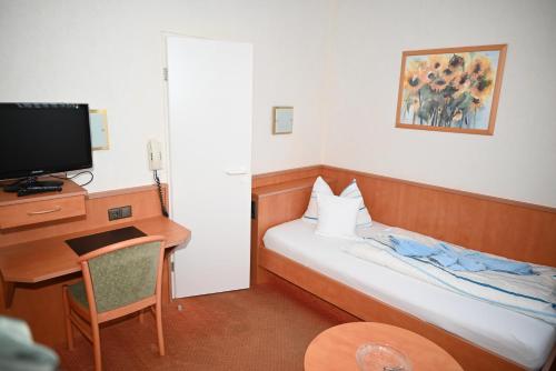 Habitación de hotel con cama, escritorio y TV. en Hotel Passat en Borkum