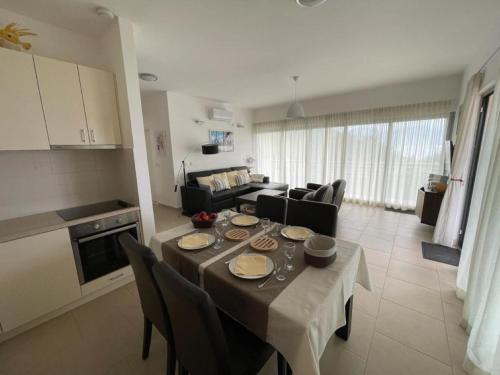 eine Küche und ein Wohnzimmer mit einem Tisch und Stühlen in der Unterkunft Acacia Hill Apartment C01 in Ðenovići