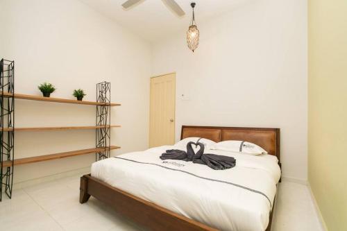 a bedroom with a bed with two black shoes on it at BalikPulau Cozy Home 4BR w BBQ in Balik Pulau