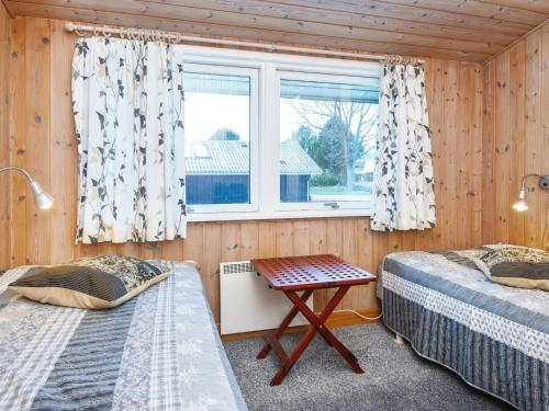 ヒュールスミンネにあるHoliday home Juelsminde IXの窓とテーブル付きの部屋のベッド2台