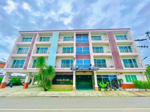 a large pink building with palm trees in front of it at Al Ameen Hotel in Krabi