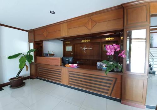 a lobby with a counter with pink flowers in it at Al Ameen Hotel in Krabi