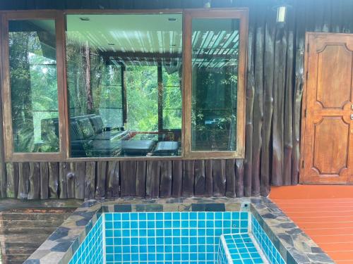 a house with a swimming pool in front of a window at คุ้งน้ำ รีสอร์ท นครนายก in Ban Khao Kariang (1)