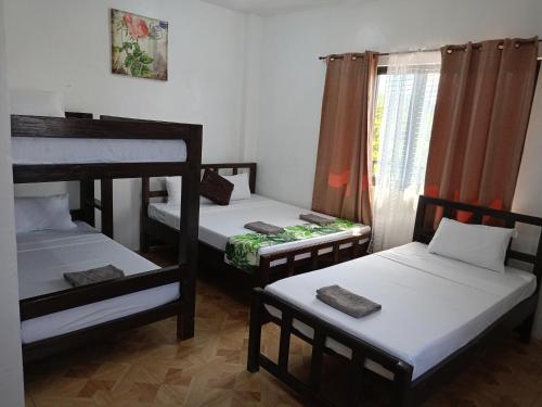 three bunk beds in a room with a window at Alec Lodge in Coron