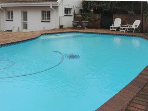 a large blue swimming pool in front of a house at Gentle Breeze Retreat in Parys