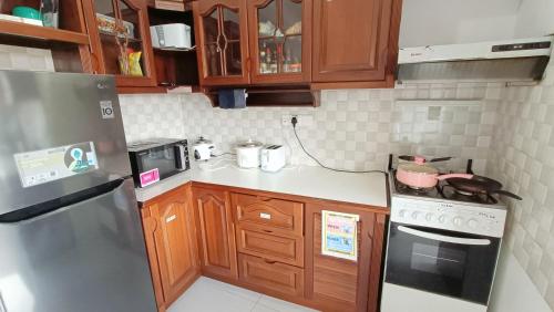 a kitchen with wooden cabinets and a stainless steel refrigerator at Smile Hub Kandy -Youth Hostel- in Kandy